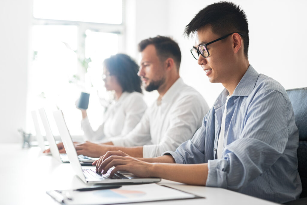 asian man using laptop near colleagues in office