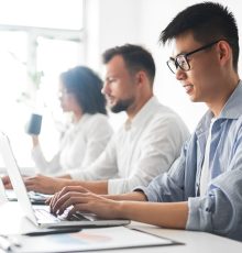 asian man using laptop near colleagues in office
